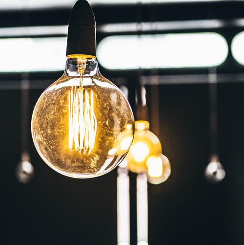 A vintage-style lightbulb is hanging in the foreground of the picture, in the background there are several other lightbulbs.