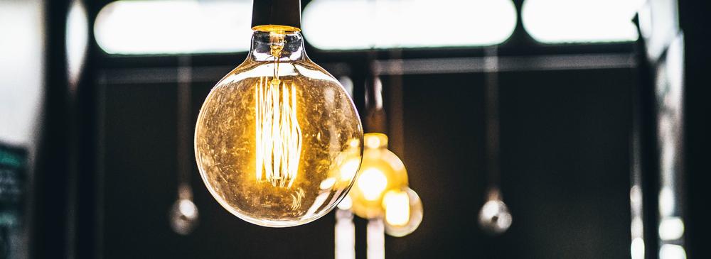 A vintage-style lightbulb is hanging in the foreground of the picture, in the background there are several other lightbulbs.