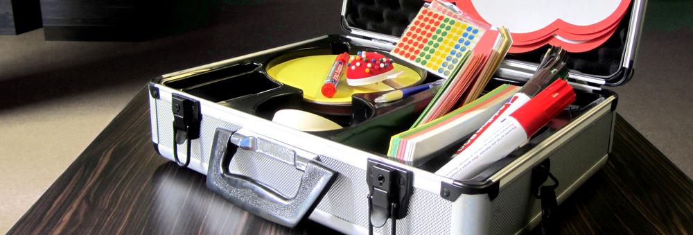 A metal presentation case with filing cards, pens, stickers and pins.