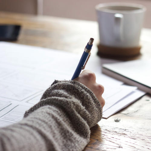 Hand writing with a pen on a piece of paper on wooden table